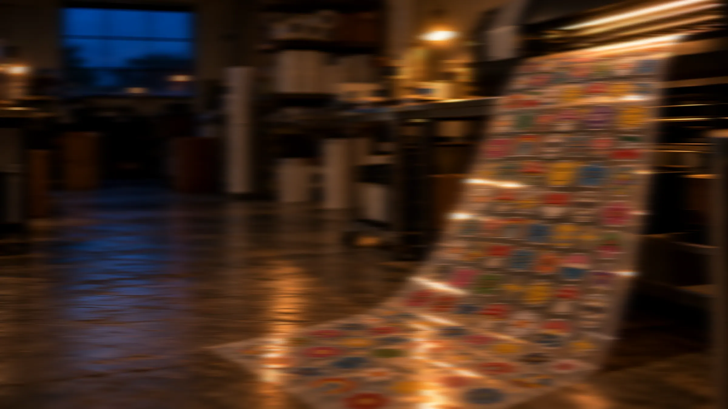 A print shop after hours: a long gang sheet of DTF transfers curls out of the printer under warm lamps.
